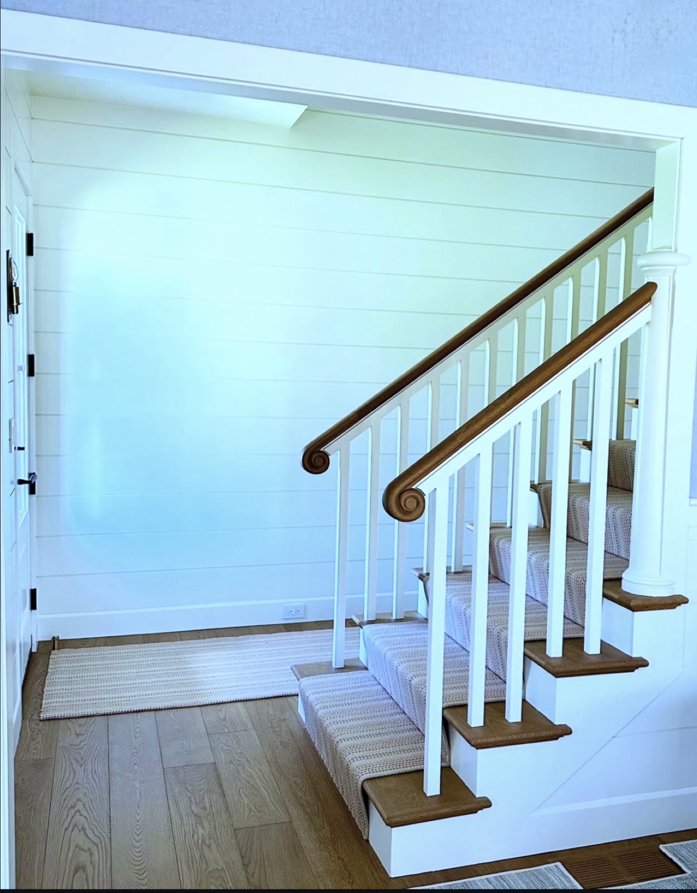 Custom staircase with oak handrails and white architectural millwork